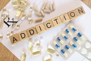 Word addiction collected with wooden cubes on white paper with medicines
